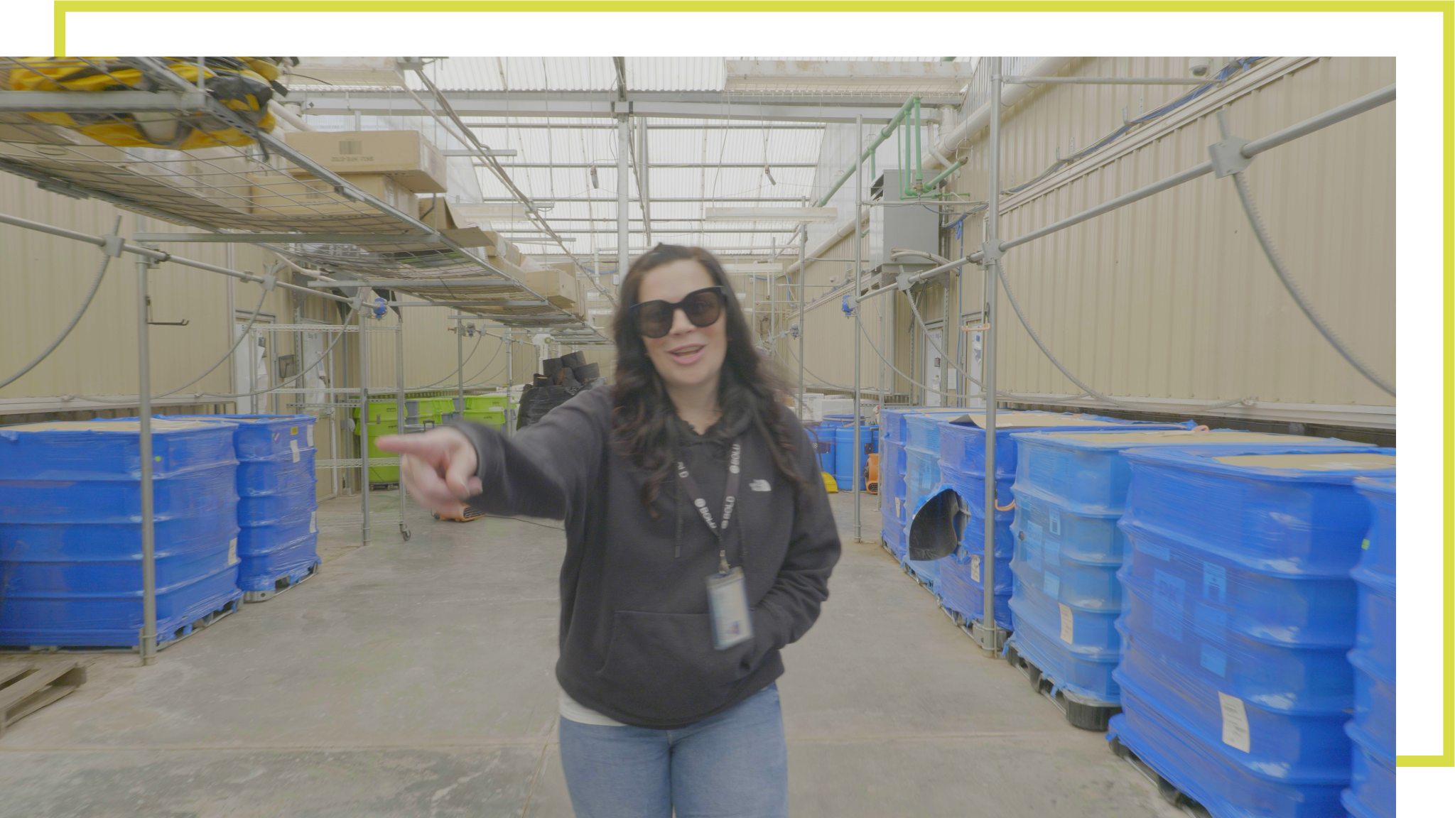 Annie Iselin BOLD Cannabis Senior Director of Operations inside BOLD’s cultivation facility with blue processing containers and greenhouse infrastructure.