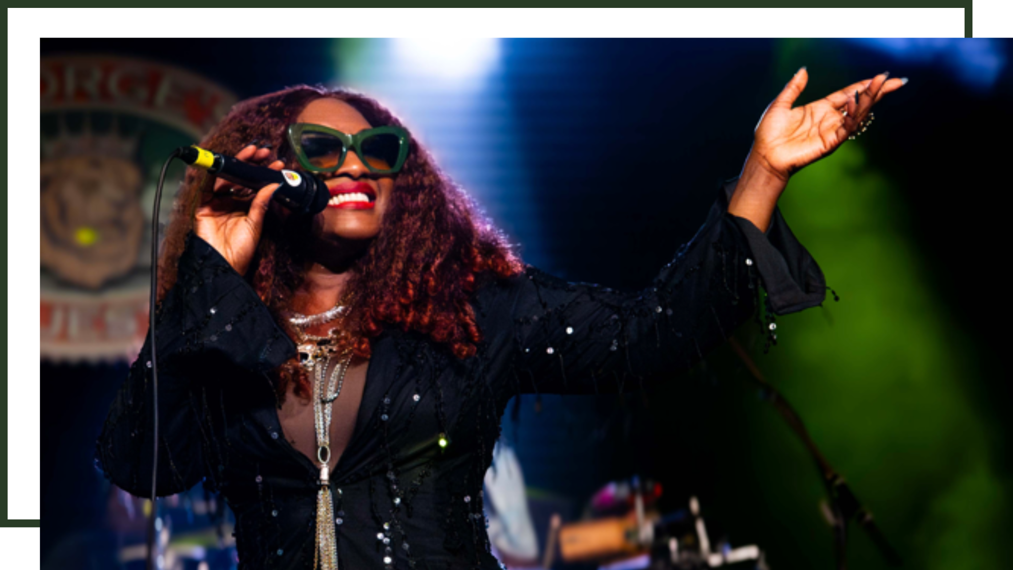 Rochelle Bradshaw performing a live reggae concert with microphone and sunglasses at Northwest Arkansas music venue.